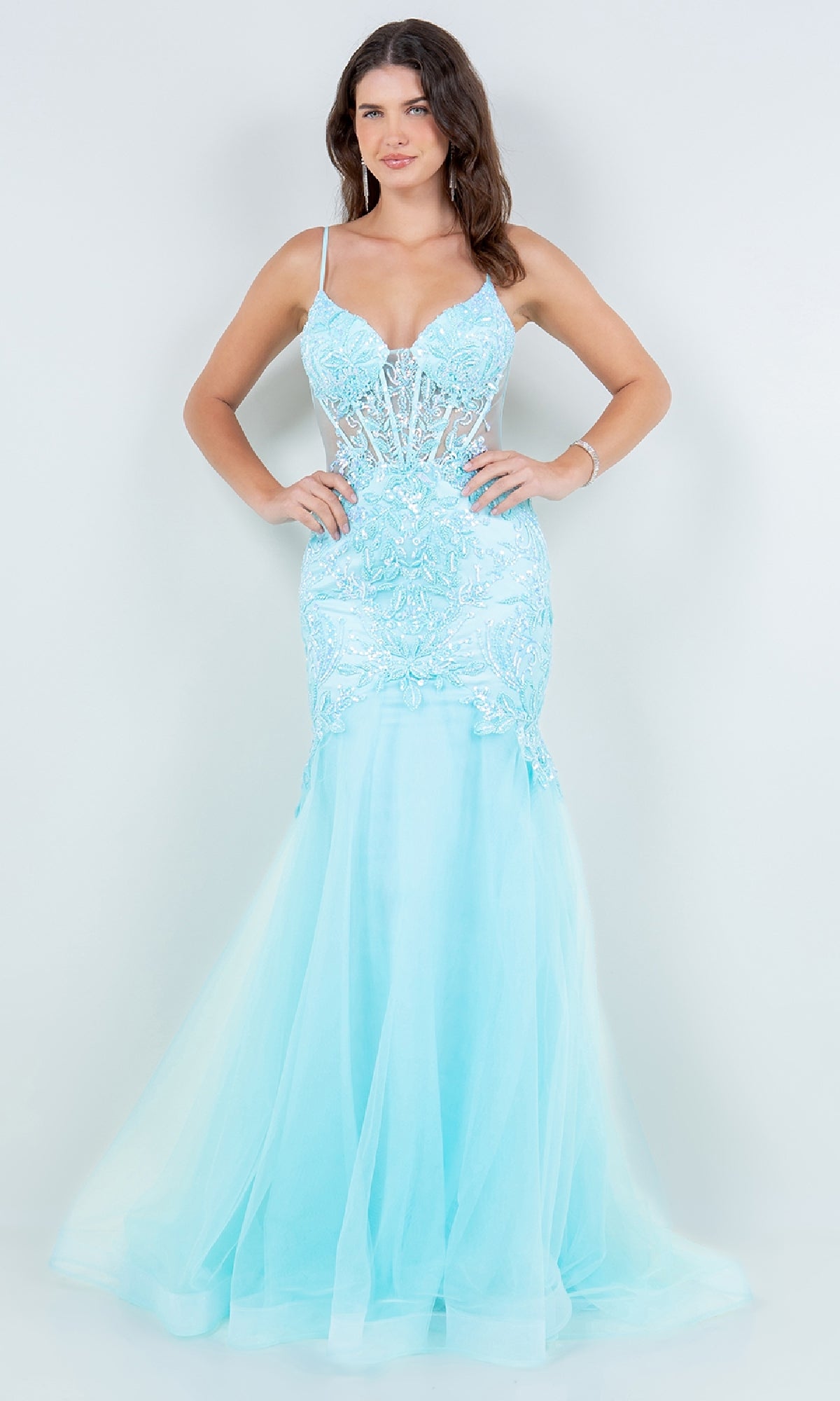 A woman stands against a plain background wearing the Long Mermaid Prom Dress: Cinderella Couture 8276J in light blue, featuring sleeveless design, lace detailing, and sheer panels.
